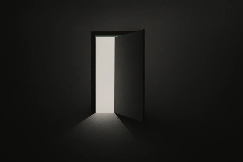 Puerta entreabierta dejando pasar luz en la oscuridad, símbolo de salida de la autoayuda engañosa